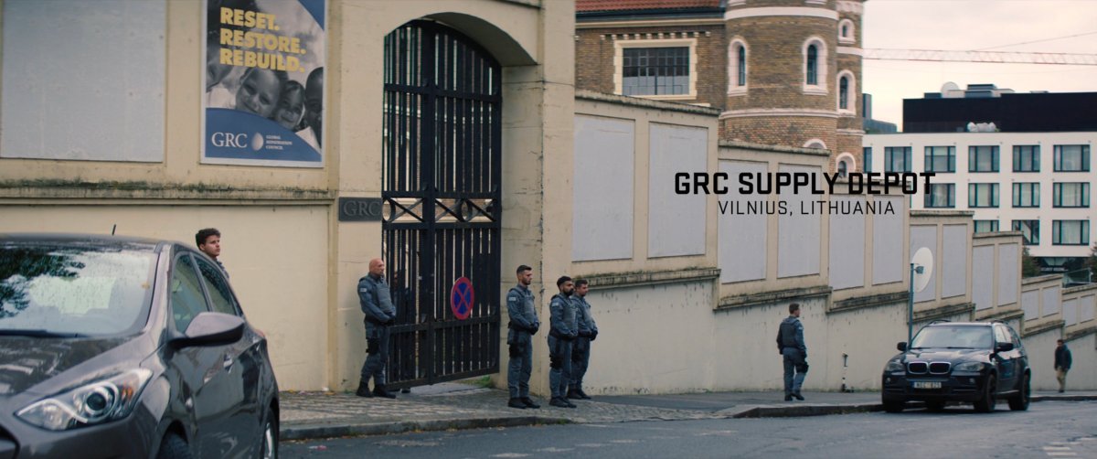 Soldiers stand in front of gates at a GRC Depot. Text: GRC Supply Depot, Vilnius, Lithuania.
