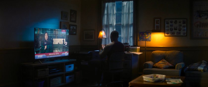 Sam watching a news report from outside the GRC Council building.