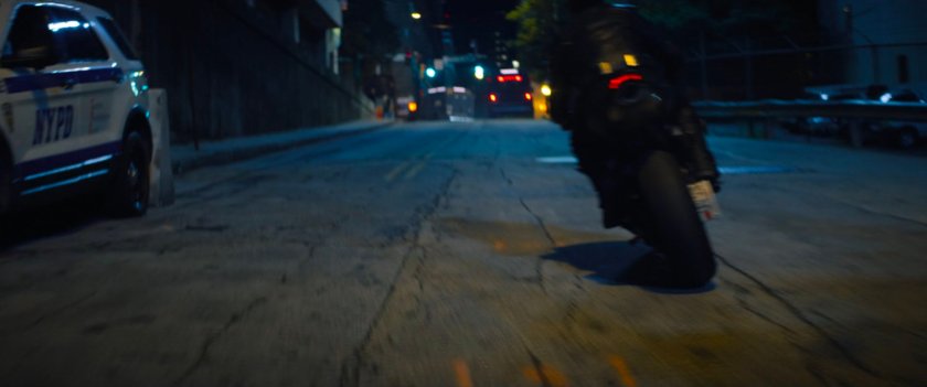 Motorcycle speeding out of a dark New York alley.