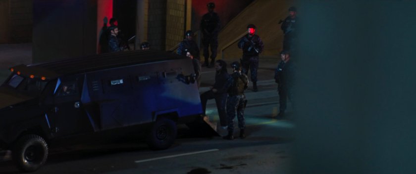 Prisoners loaded into armored car in underground parking structure.