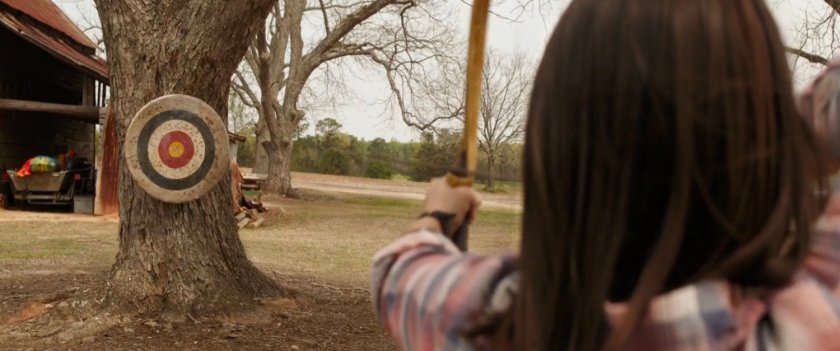 Lila Barton aims a bow and arrow at a target.