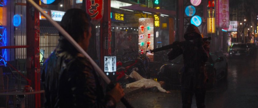 Ronin confronts another man with a sword on a shiny neon nighttime Tokyo street.