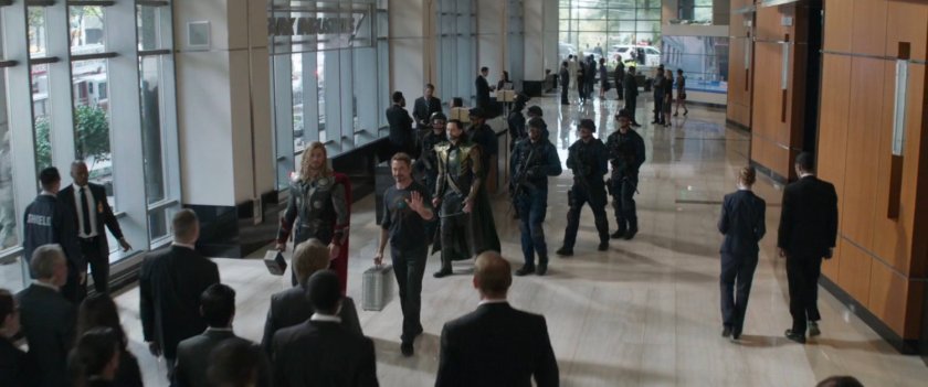 High angle of Loki, Thor and Tony Stark plus a number of guards and civilians in the Stark tower lobby.