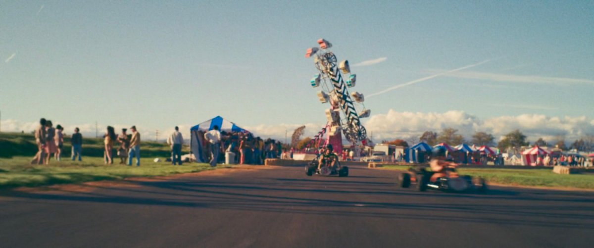 Go carts race around a track at a fair.