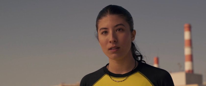 Closeup of female surfer with two red and white stripped towers behind her.