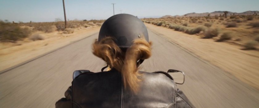 Closeup of Vers riding motorcycle of desert highway.