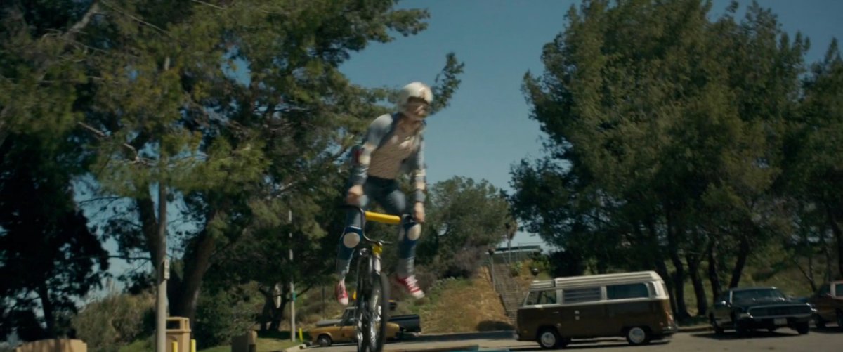 Young Carol Danvers flips over the handlebars of her bike in a park.
