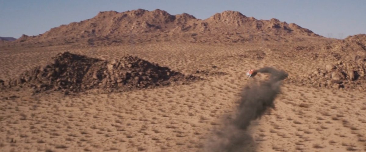 A Kree spacecraft flies out of control towards a desert hill.