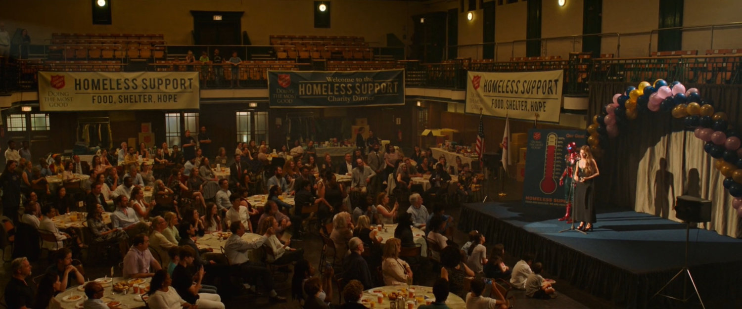 Spider-Man and May on stage at an event inside the Queen's Cultural Center.