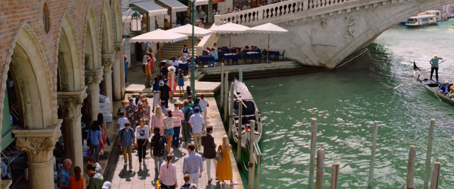 Crowds along the edge of a canal by the Rialto Bridge.