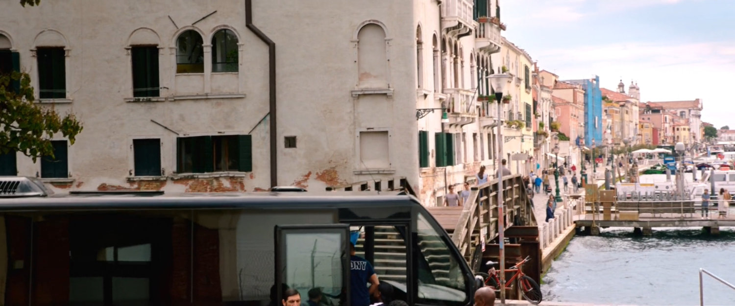View of Venice buildings and canal over the top of a black tour bus.