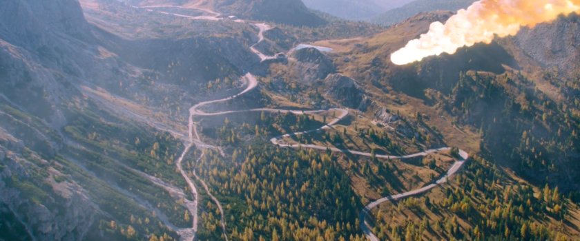Aerial view of winding mountain road with rocket heading towards it.