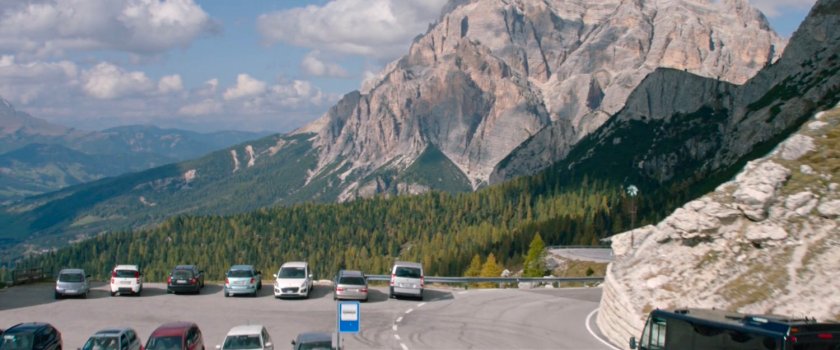 Parking area off mountain road, with giant peaks in the background.