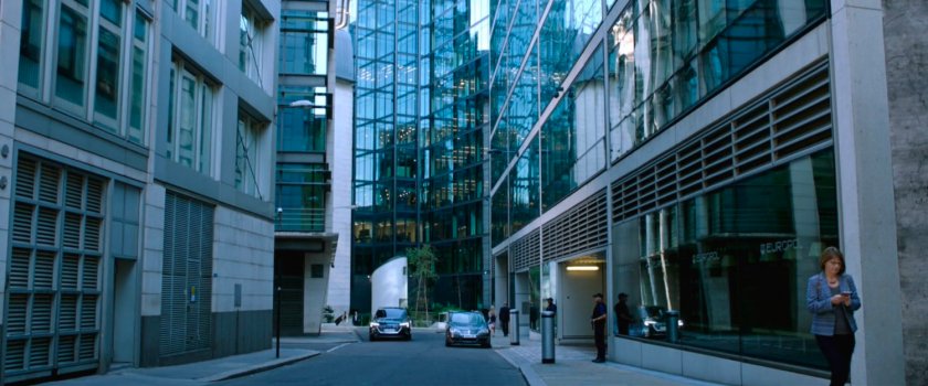 Cars on a street outside modern office buildings.
