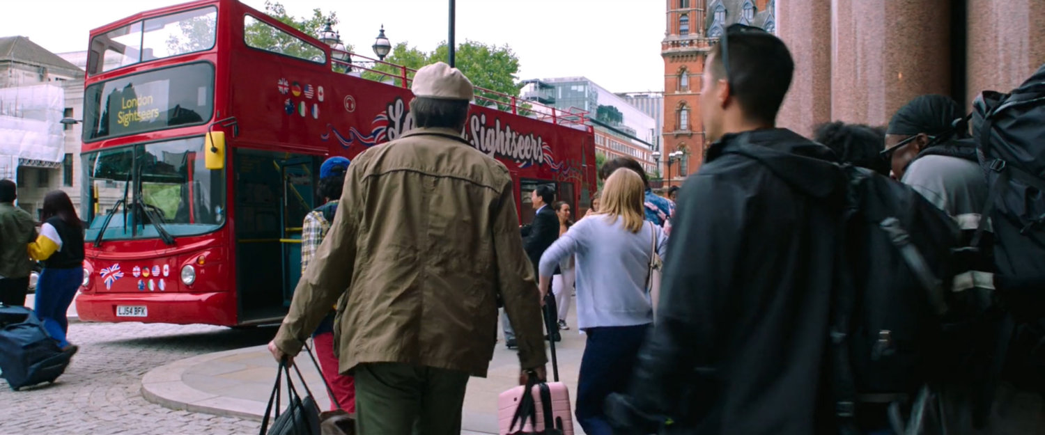 Students and teachers outside London train station board red double decker bus.