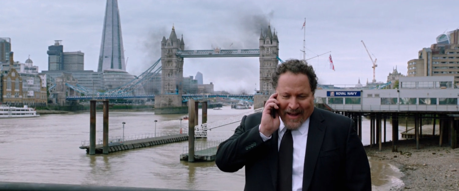 Happy Hogan on the phone with pier and smoking Tower Bridge behind him.