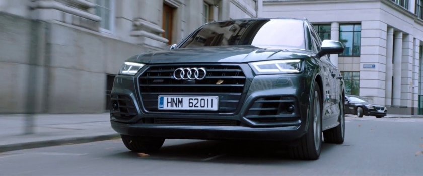A car driving on a London street. License plate: HNM 62011.