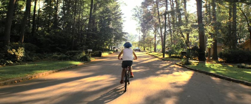 Young Natasha riding bike on suburban street.