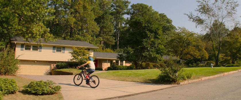 Young Natasha riding bike onto suburban home driveway.