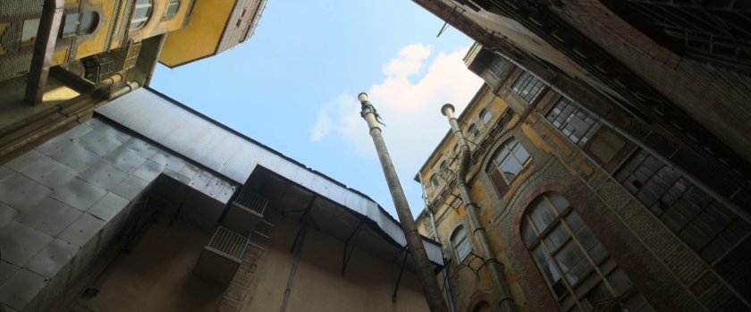 Low angle of toppling smokestack from courtyard of Budapest apartment.