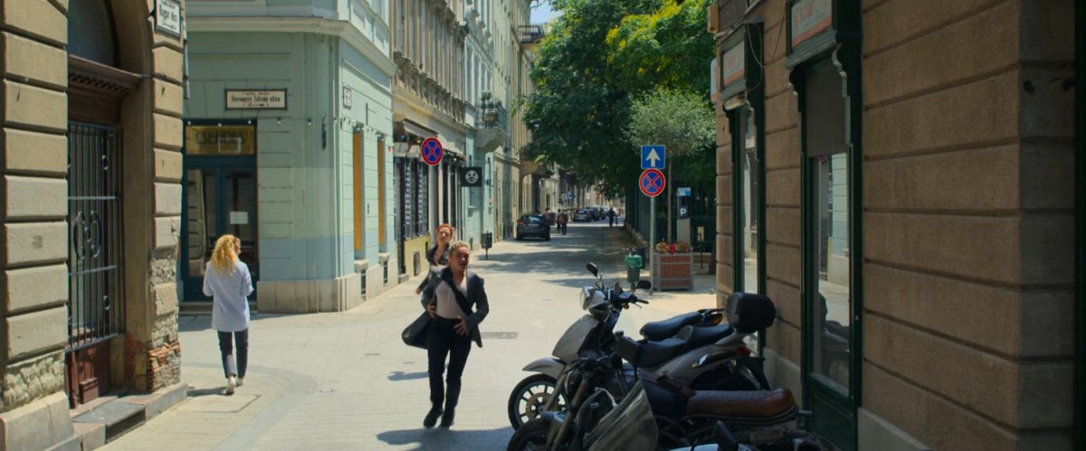 Yelena and Natasha run into Budapest alley by motorcycles.