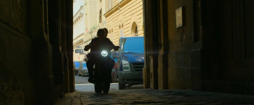 Motorcycle drives through Budapest archway.