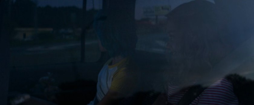 Young Natasha and Yelena in back of car with partial view of road outside windows.