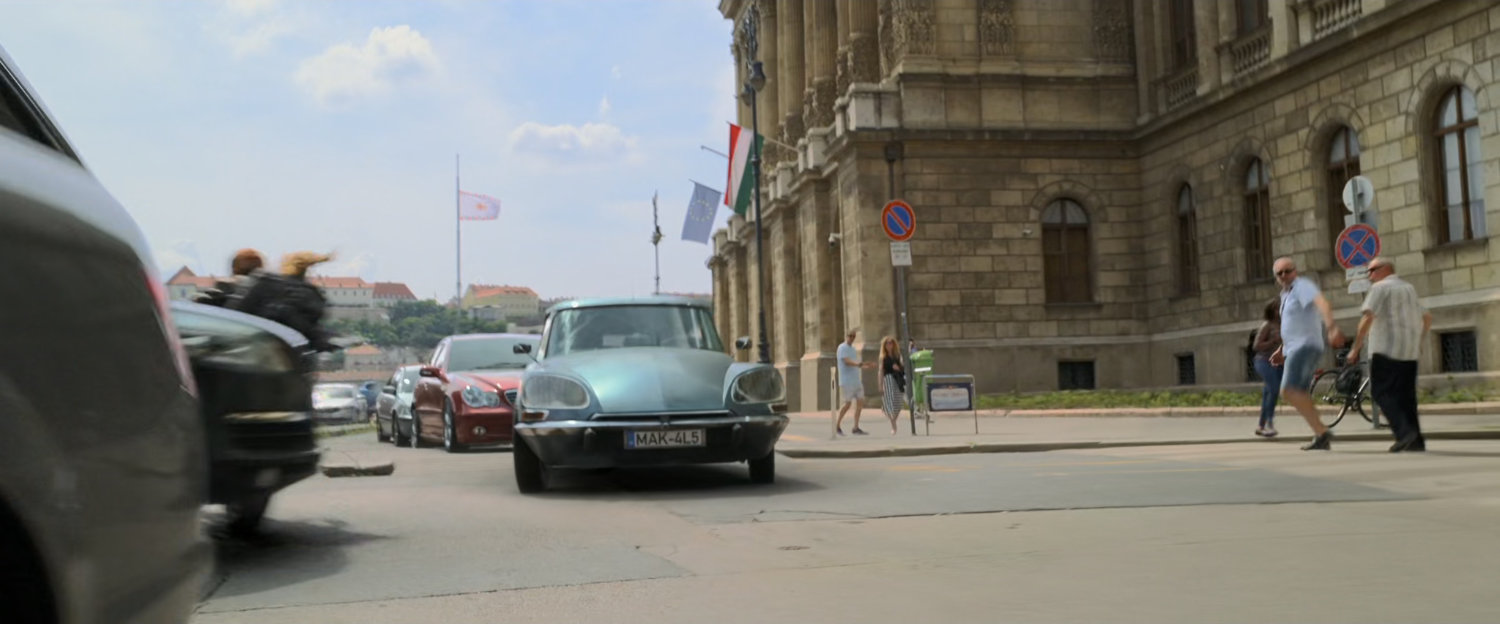 A motorcycle jumps over a small car on a Budapest street.