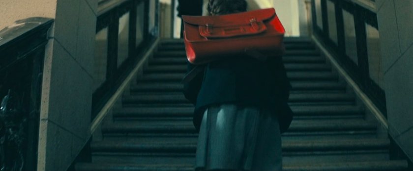 A young girl with red backpack walks up stairs.