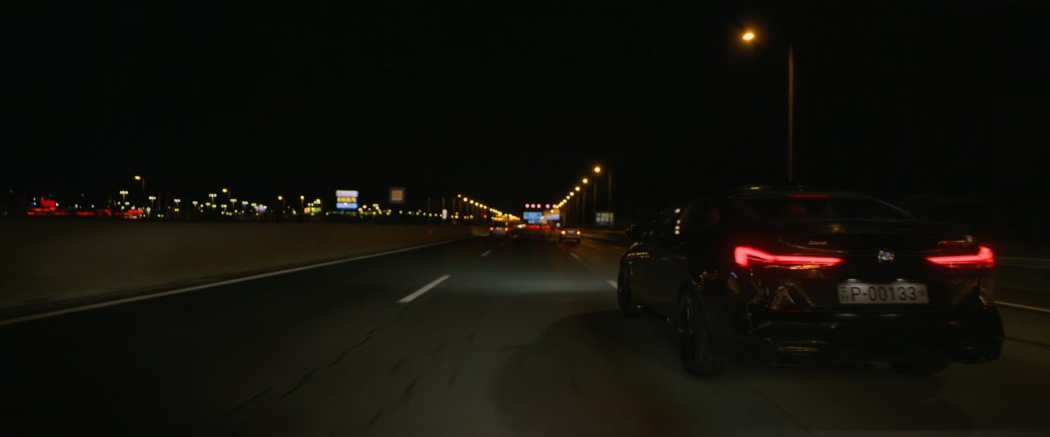 A car on a highway at night with city lights in background.