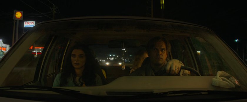 Alexei and Melina in family car with Shell and Exxon signs outside.