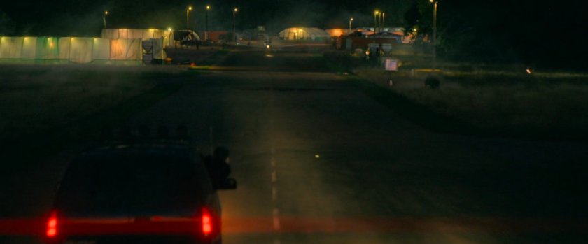 Car driving on runway towards oncoming Cessna in small airfield.