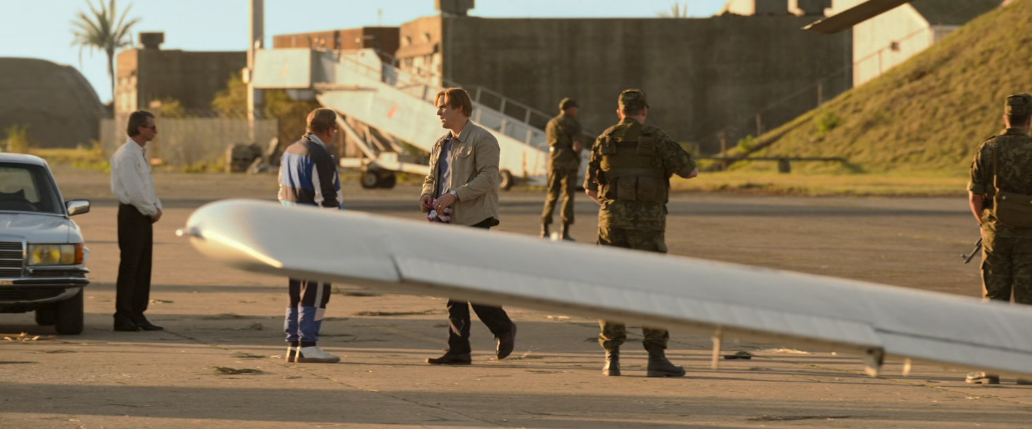 Alexei and Dreykov standing behind Cessna wing on Cuban runway.