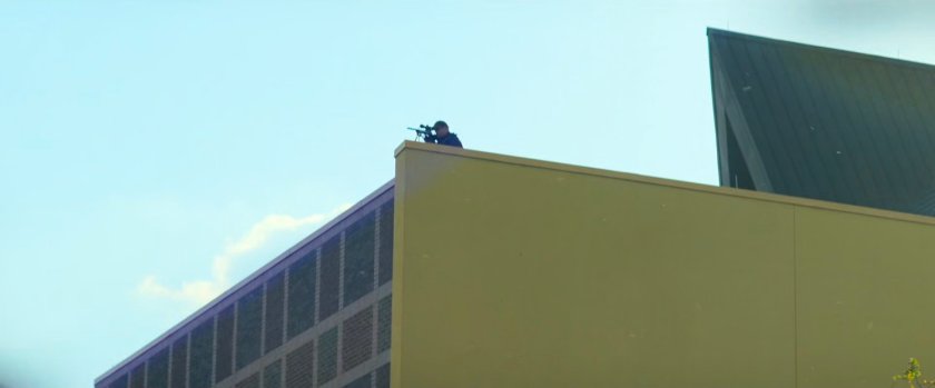 A SWAT sniper peering over a rooftop.