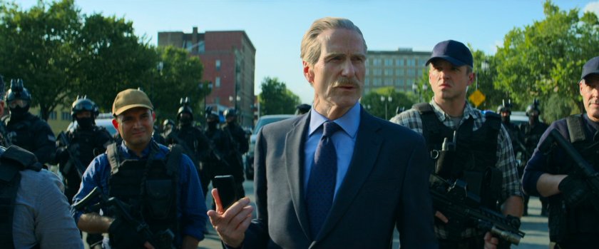 General Ross outside train terminal talking to his team.