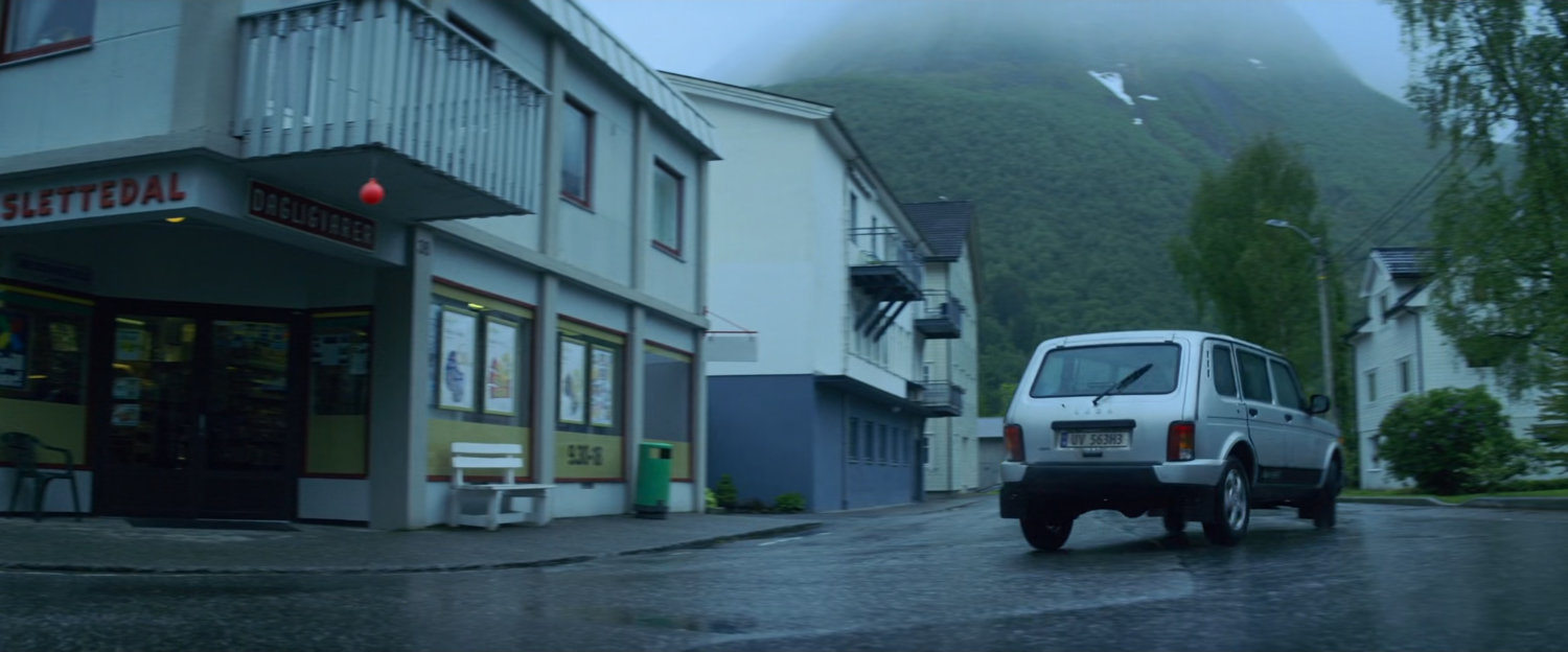Car driving away from corner grocery store in Norway.