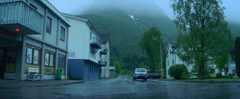 Car driving away from corner grocery store in Norway.