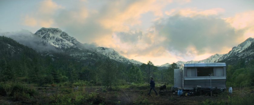 A mobile home in wooded clearing.
