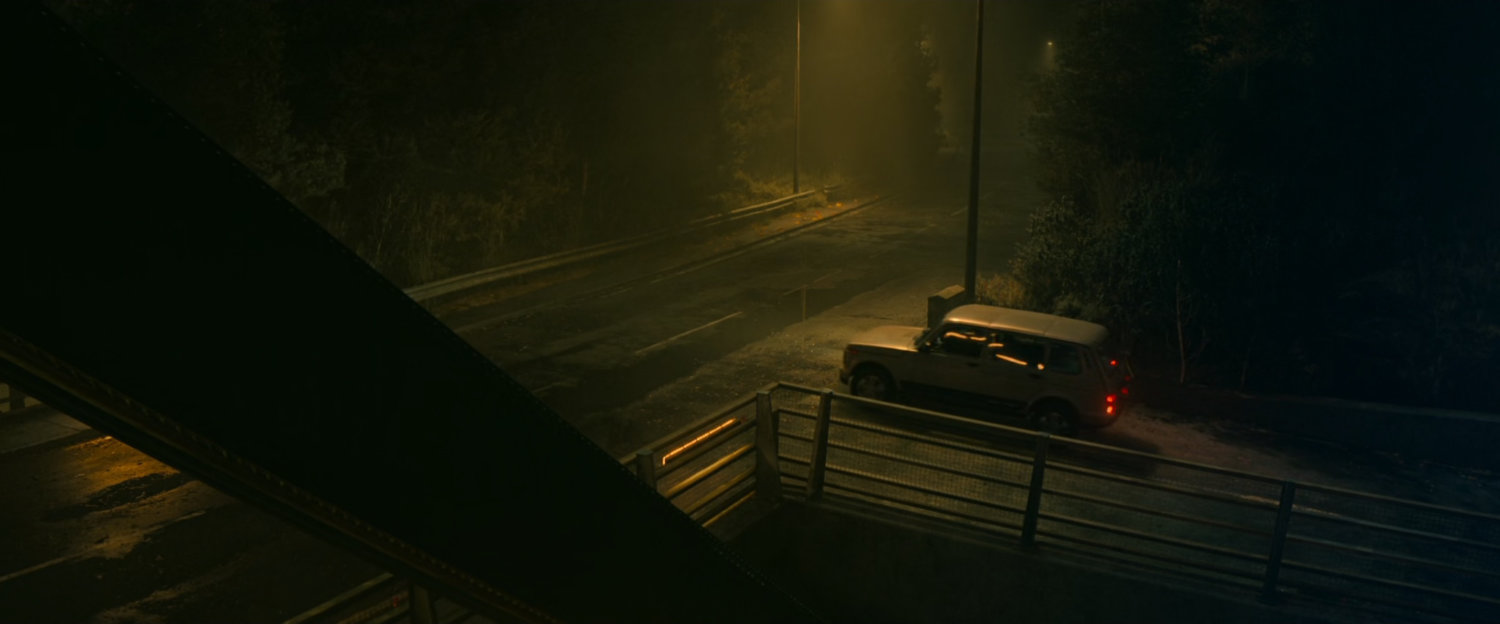 A car stopped by a foggy Norwegian bridge.