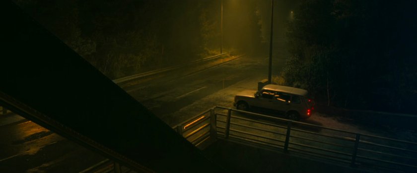 A car stopped by a foggy Norwegian bridge.