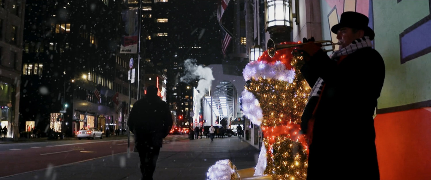 Nighttime view of trumpeter on cold snowy New York sidewalk.