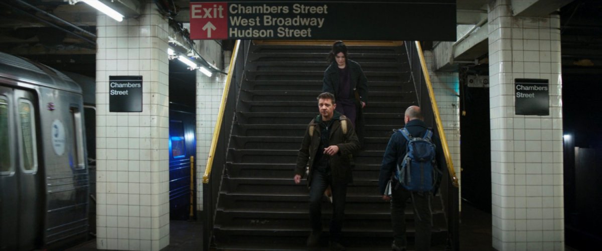 Clint and Kate descend stairs into the subway station.