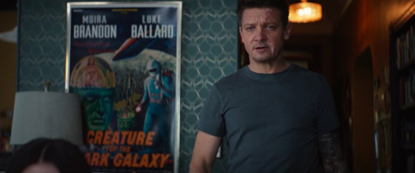 Clint inside Moira Brandon's apartment with a movie poster behind him.