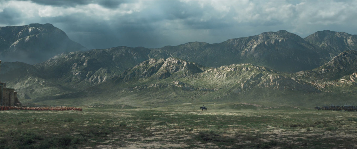 Wide angle of battle plain with mountains in background as two armies face each other.