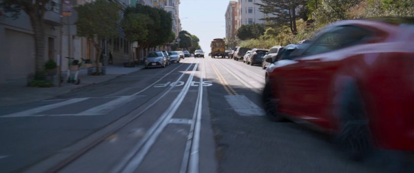 A red car driving on a street in San Francisco.