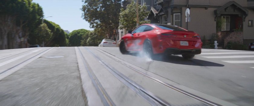 A red car braking on a street in San Francisco.