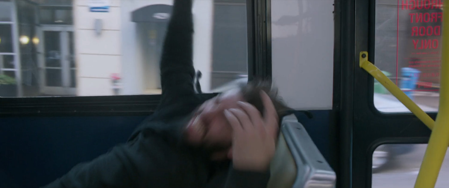 A thug falls into a seat on a San Francisco metro bus.