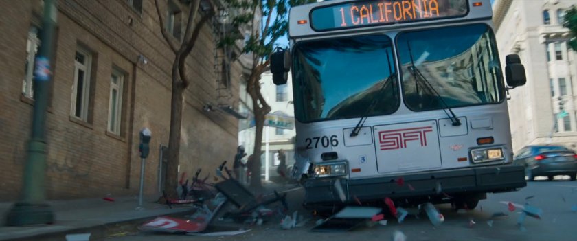 A San Francisco metro bus speeds down a hilly street running over a newspaper box.