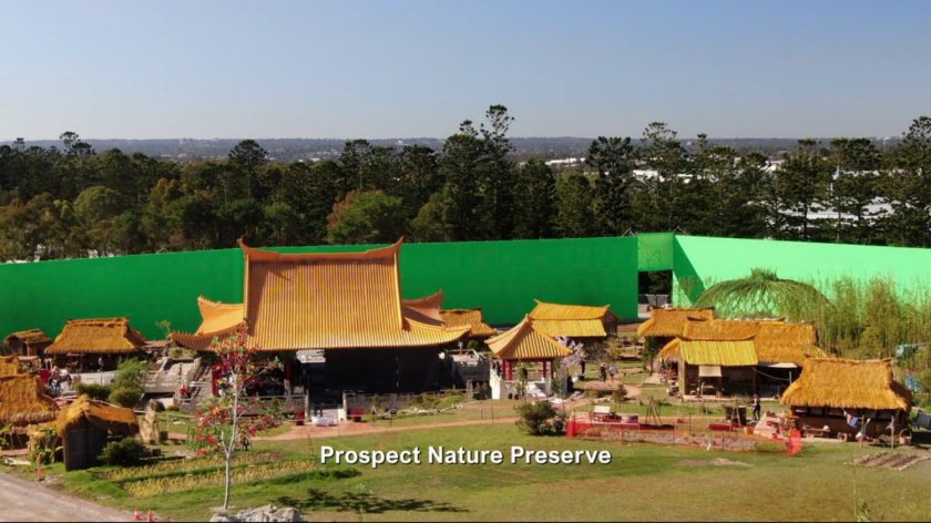 Behind the scenes of the village set with green screen behind it. Text: Prospect Nature Preserve.
