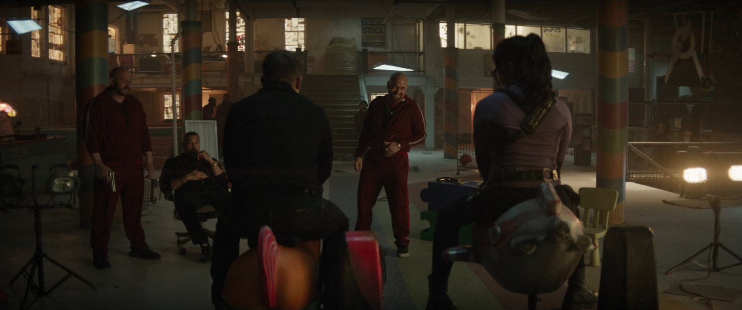 Tracksuit mafia members interrogate Clint and Kate in abandoned toy store.